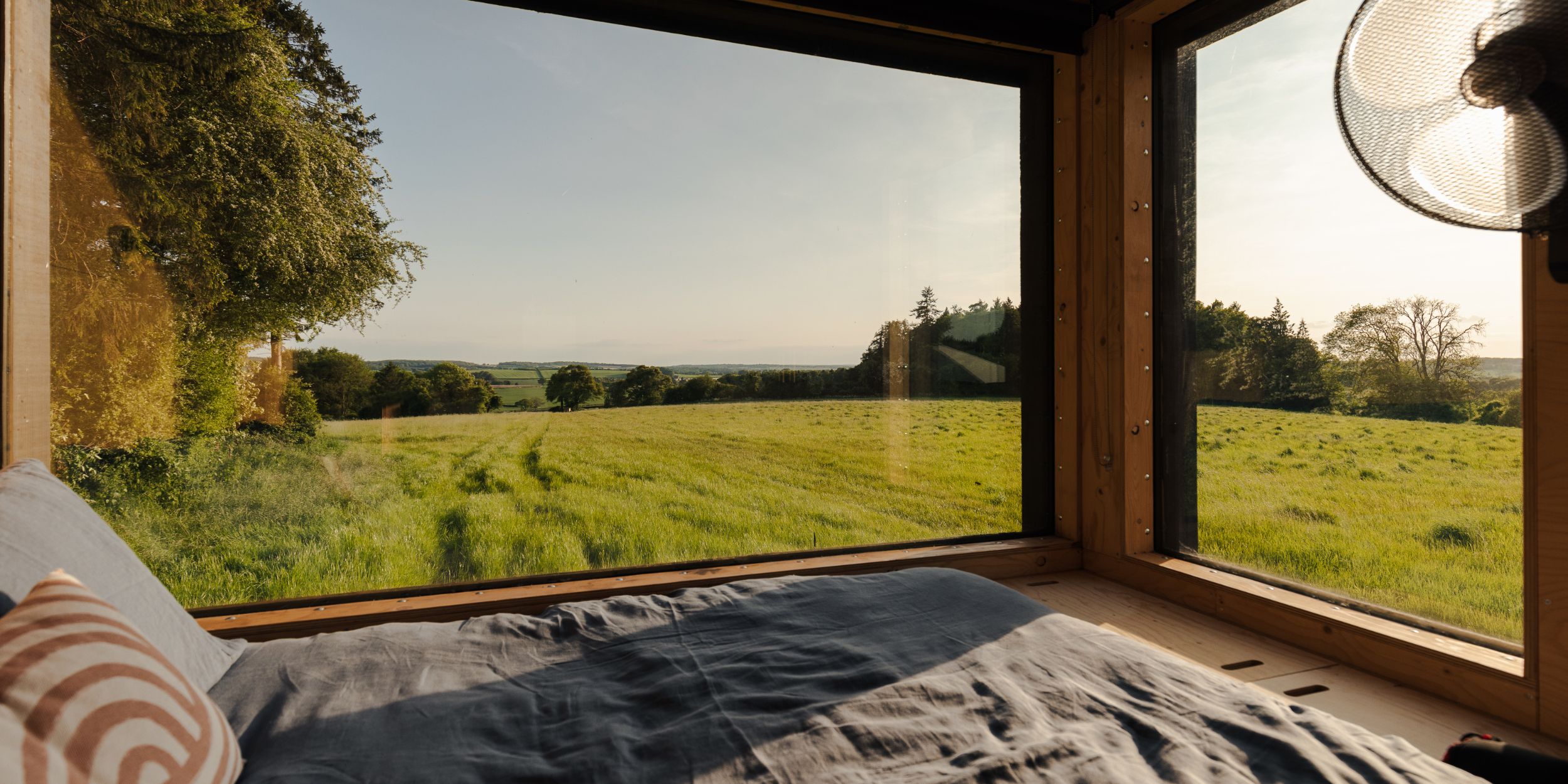 Unplugged Cabin view from the bed of the green field