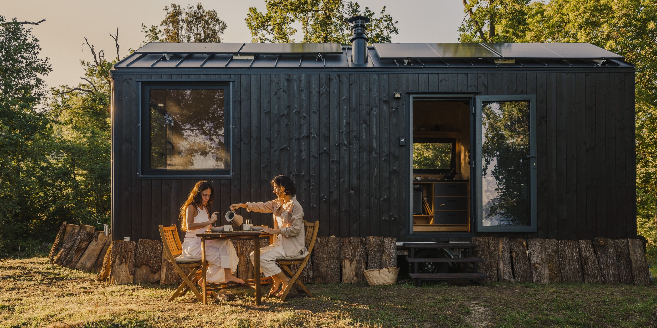 Nala Unplugged Cabin in Barcelona external view of two people having breakfast outside. Image Credit - @aripuigdomenech