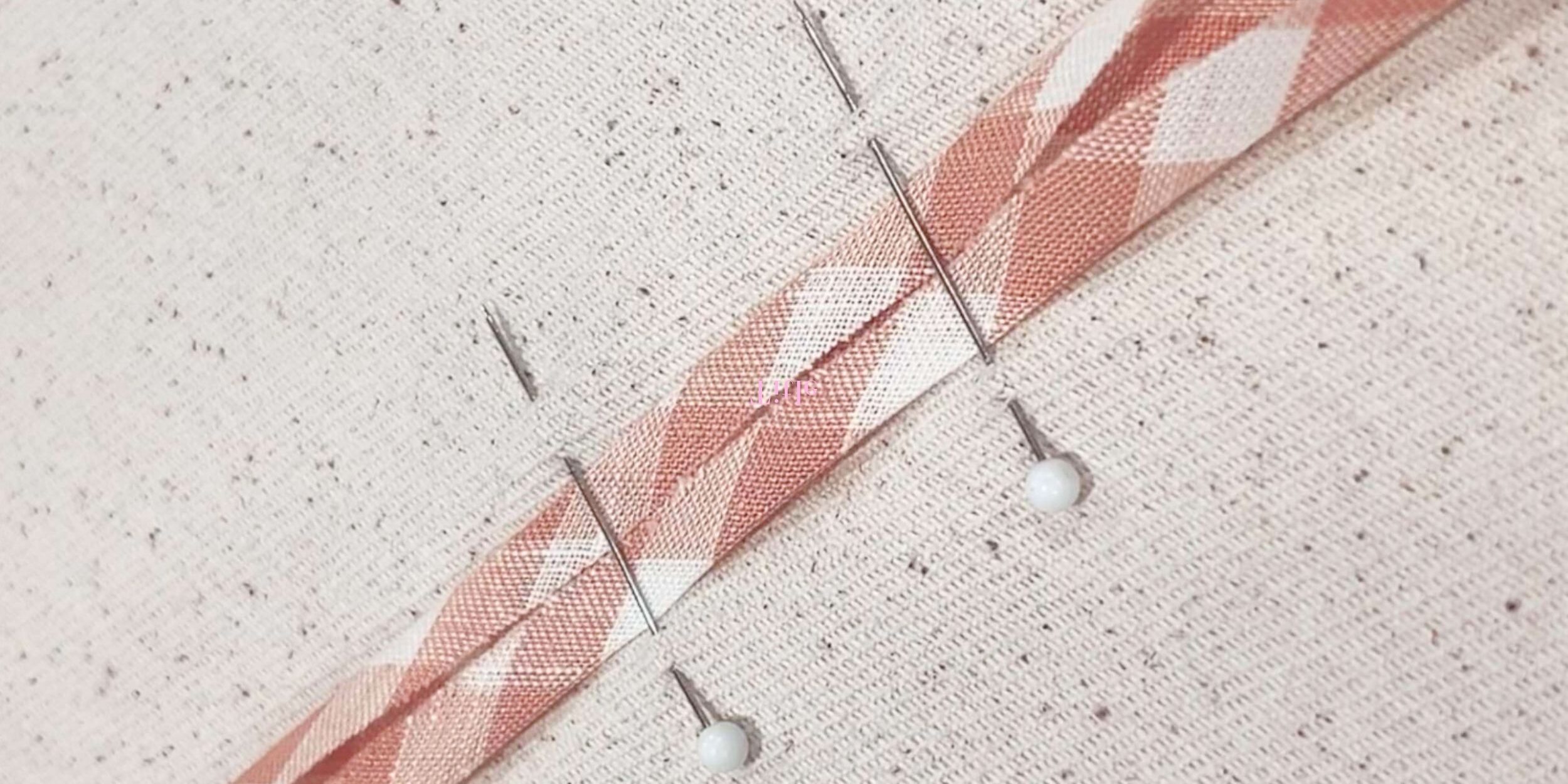 Pins holding material and bias binding in place in readiness to sew a garment together
