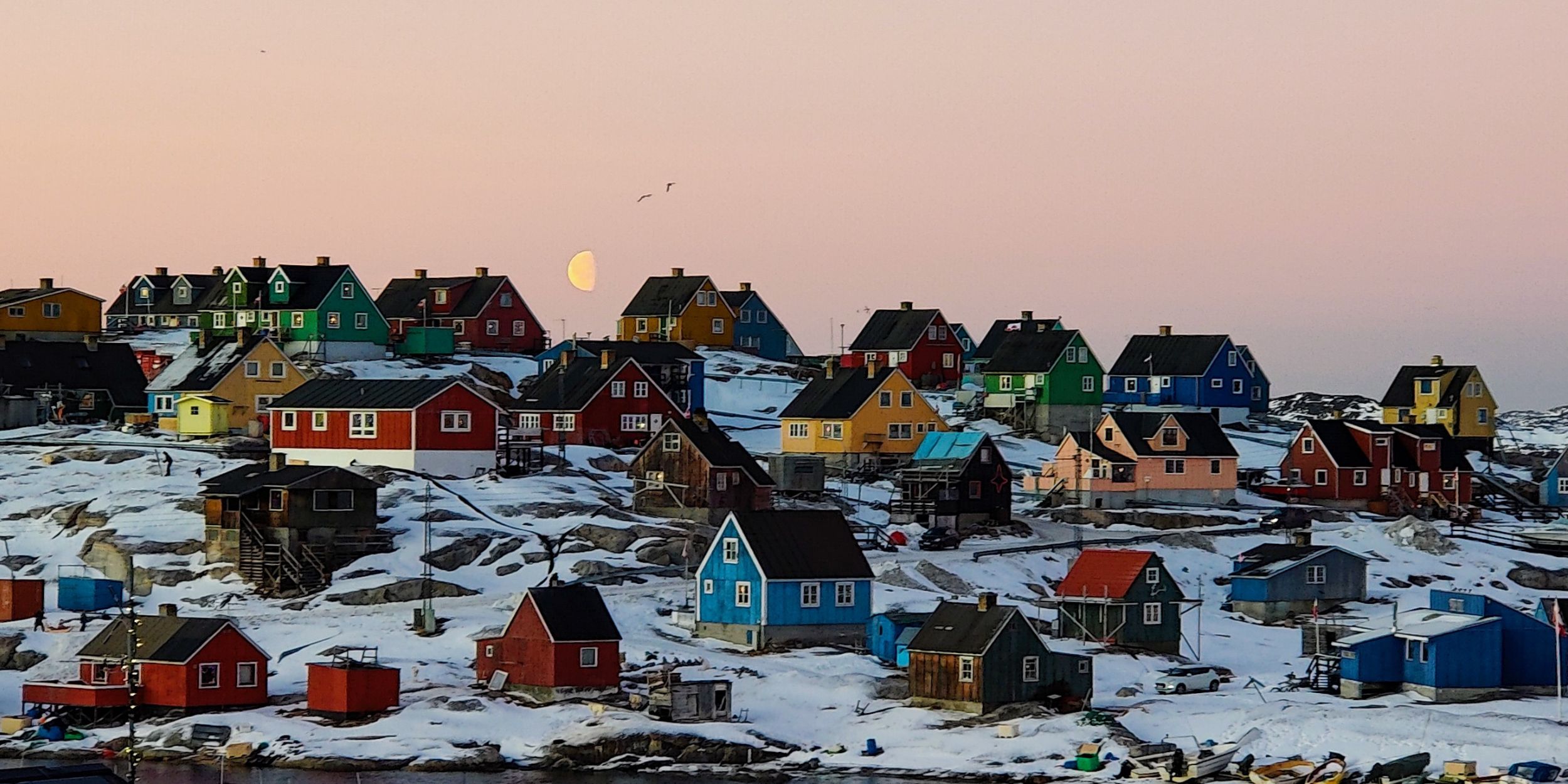 Houses in Greenland at sunset surrounded by snow