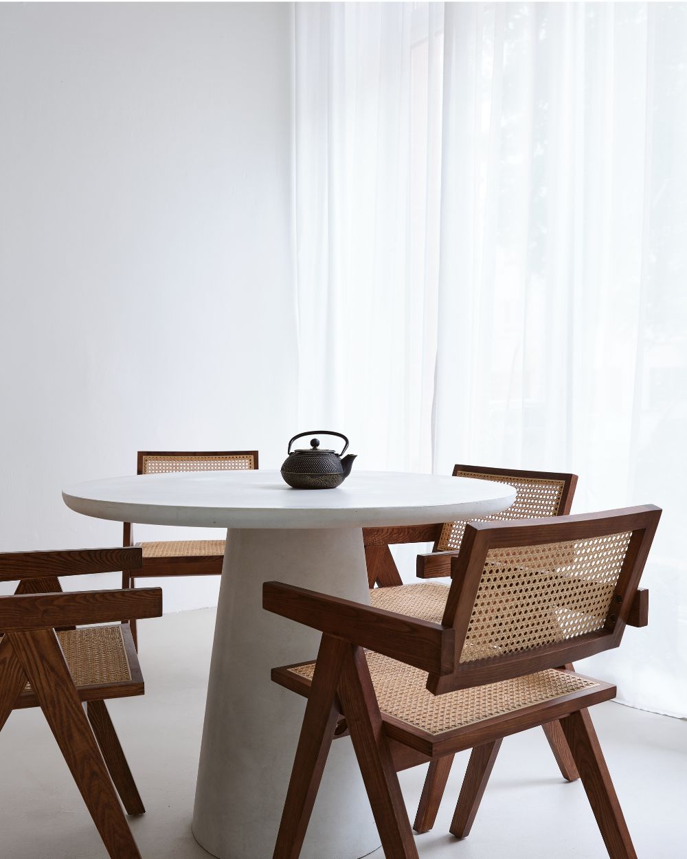 Scandinavian-style wooden chairs, and a stone table, with a teapot on it.