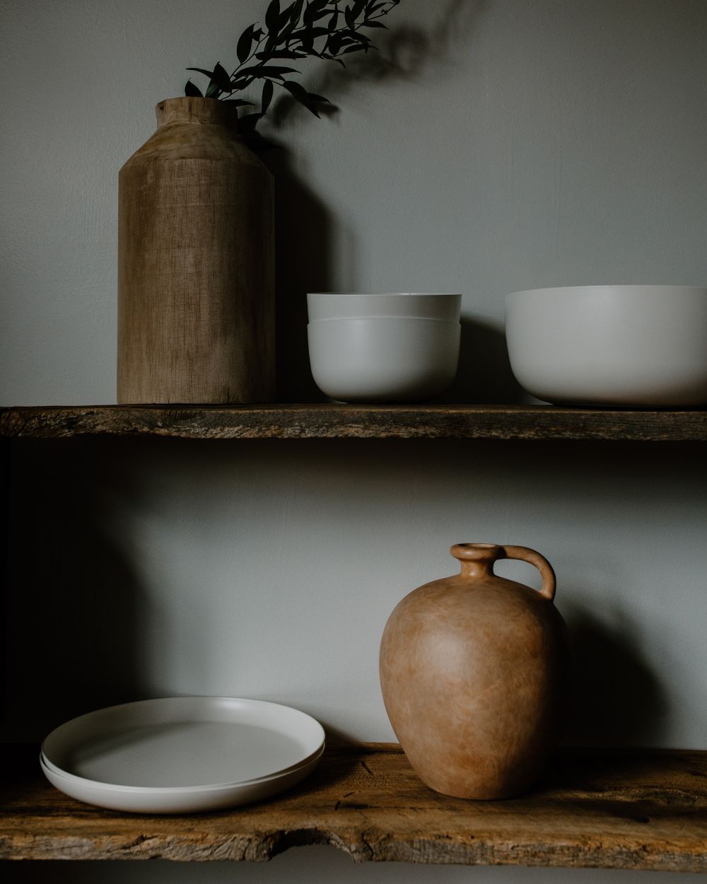 Earthenware pots, ceramic bowls, and plates on wooden shelves
