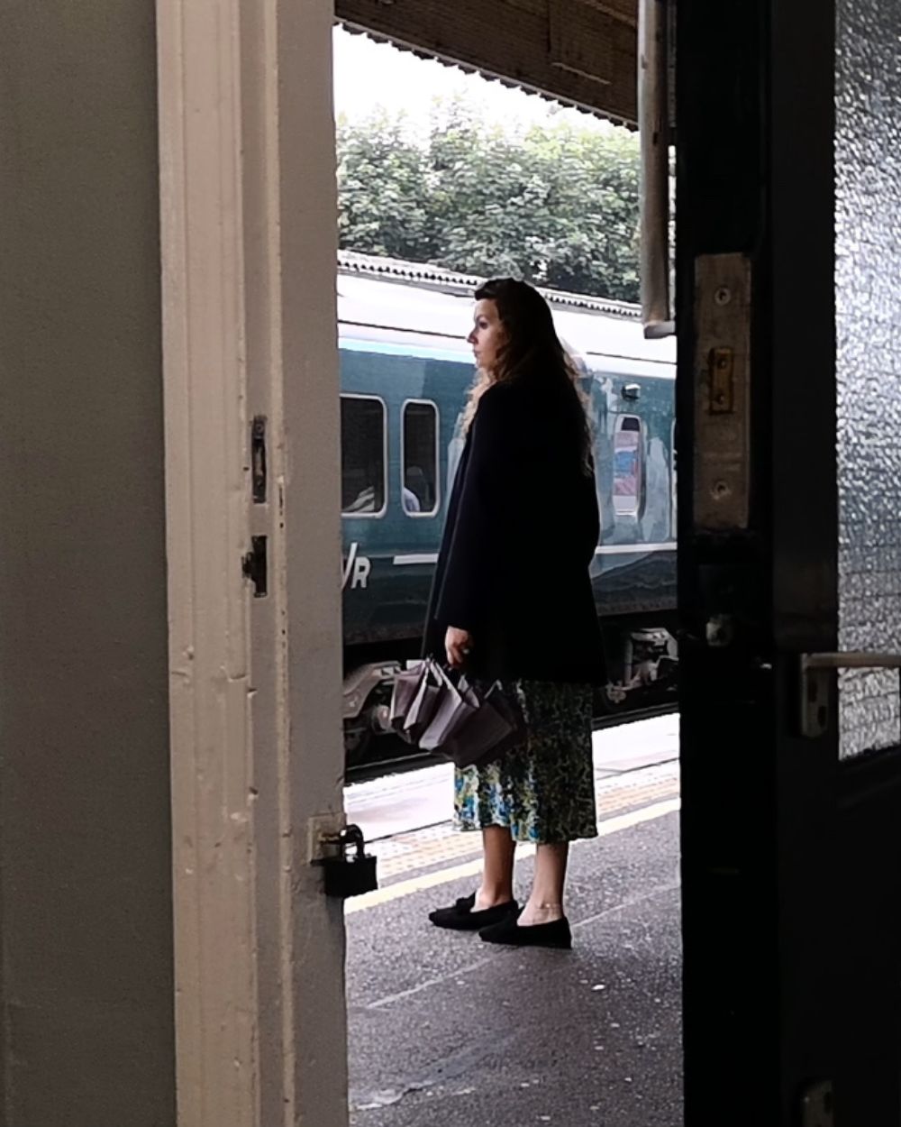 Still from the Still Here? A short film with actress and Co-Director Solène Anglaret standing at the train station