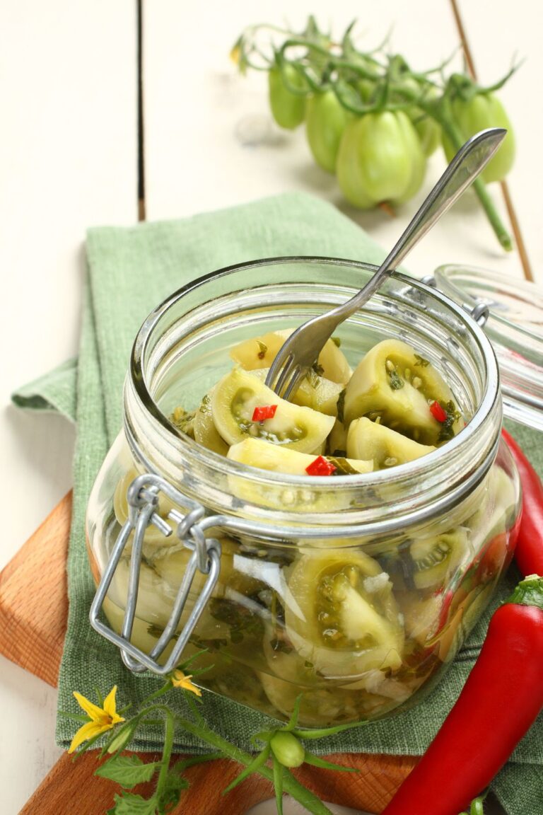 Green tomato pickles in an open jar with a fork.