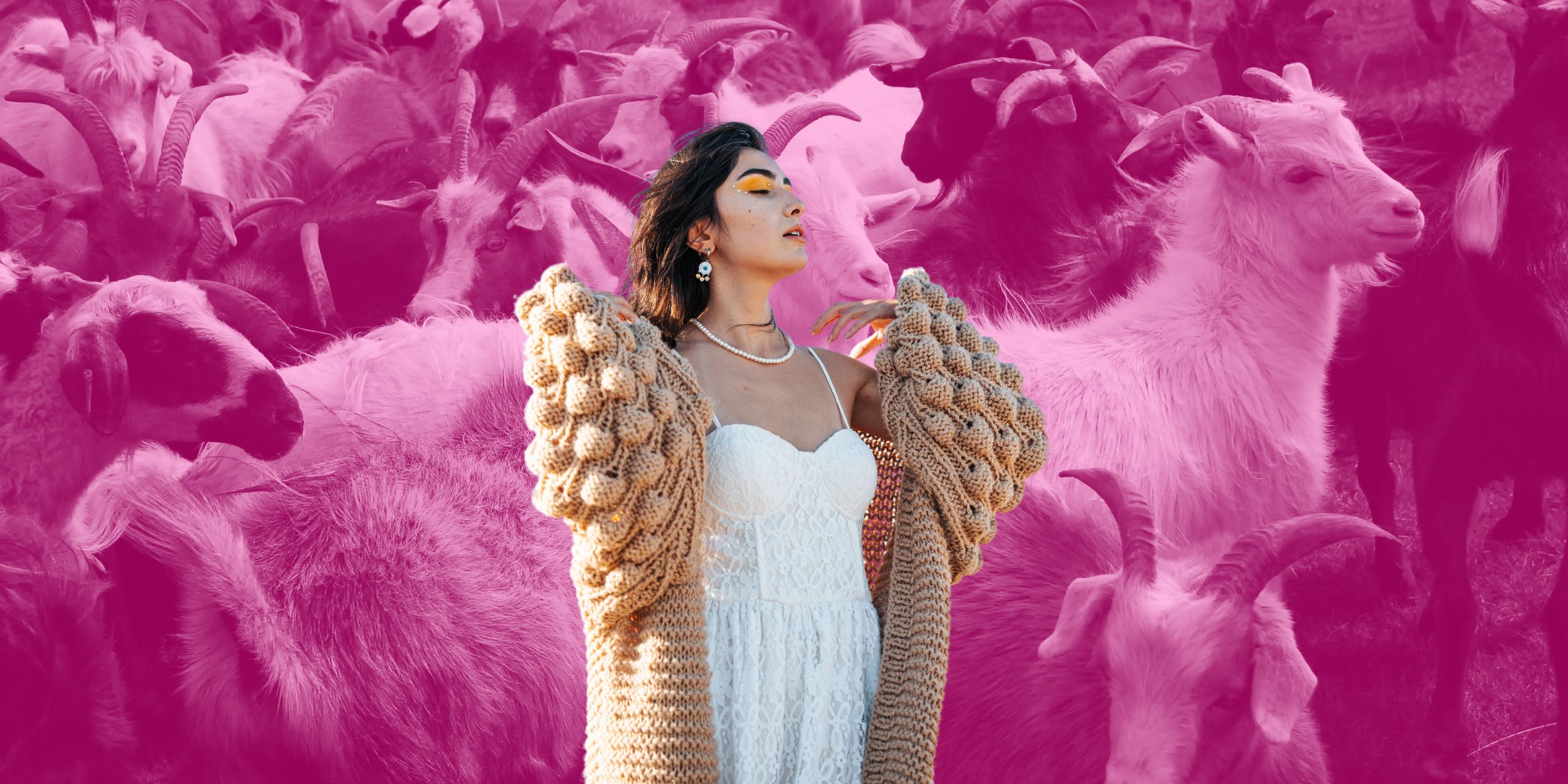 Women wearing a cashmere cardigan in front of goats