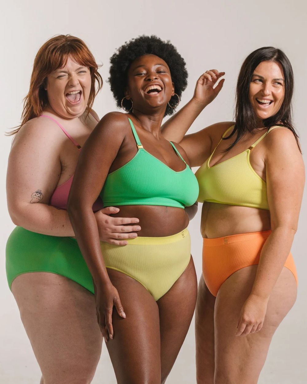 Underwear for humanity bras and briefs in green, orange and yellow on models.