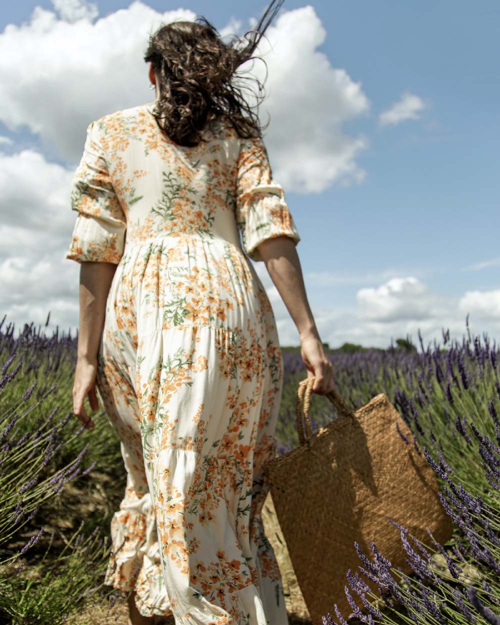 Women walking in a field in a Summer dress with a bag