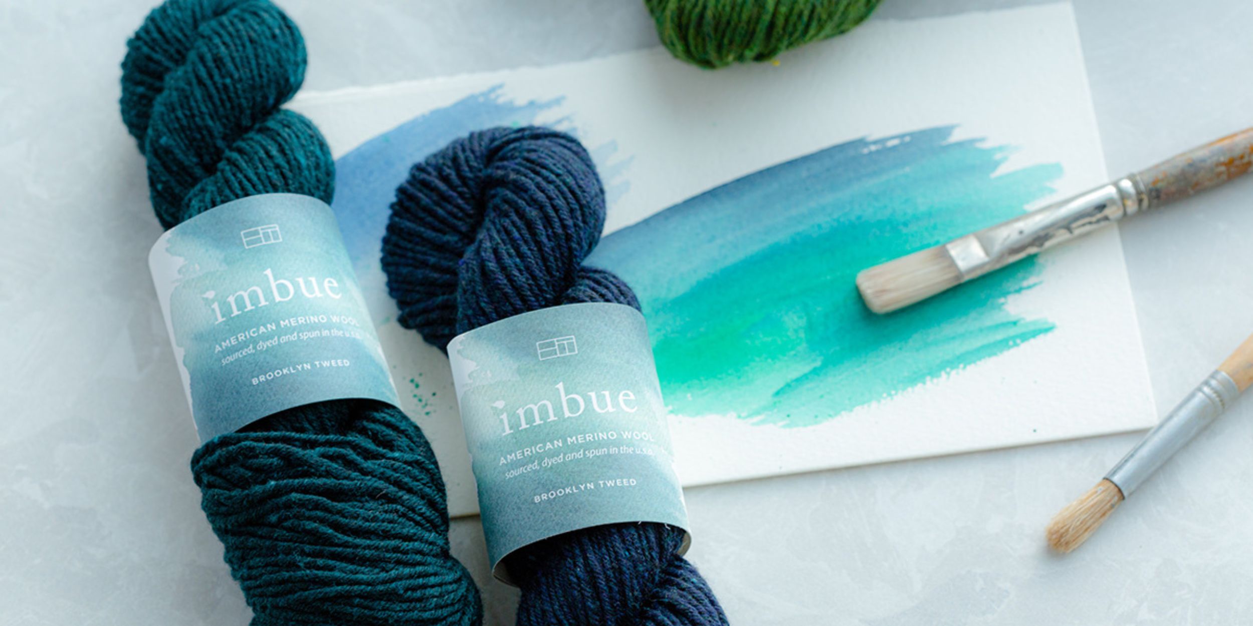 Brooklyn Tweed Imbue Yarn with a watercolour painting in blue behind it