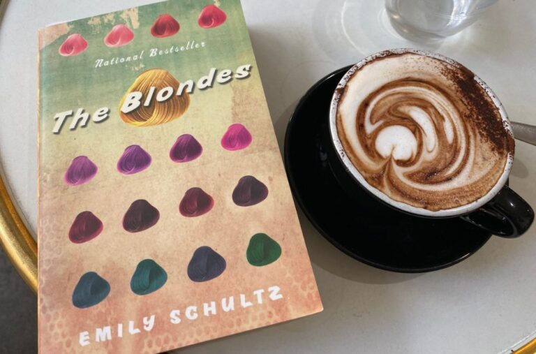 The Blondes by Emily Schultz book cover beside a cup of coffee