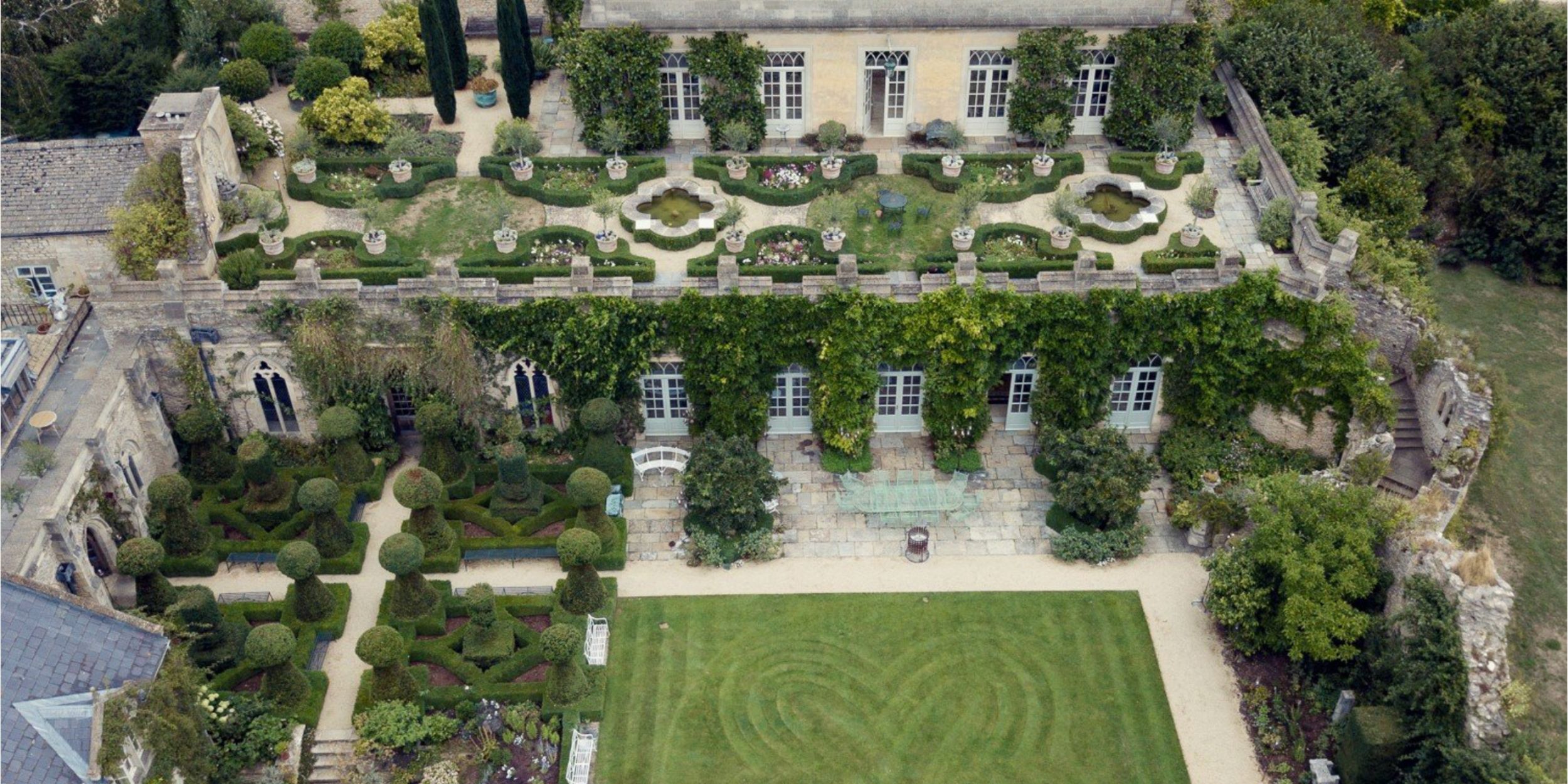 Aerial view of Euridge Manor Wedding Venue Bridal UK historical building with gardens, featuring topiary, ivy-covered walls, and decorative hedges.
