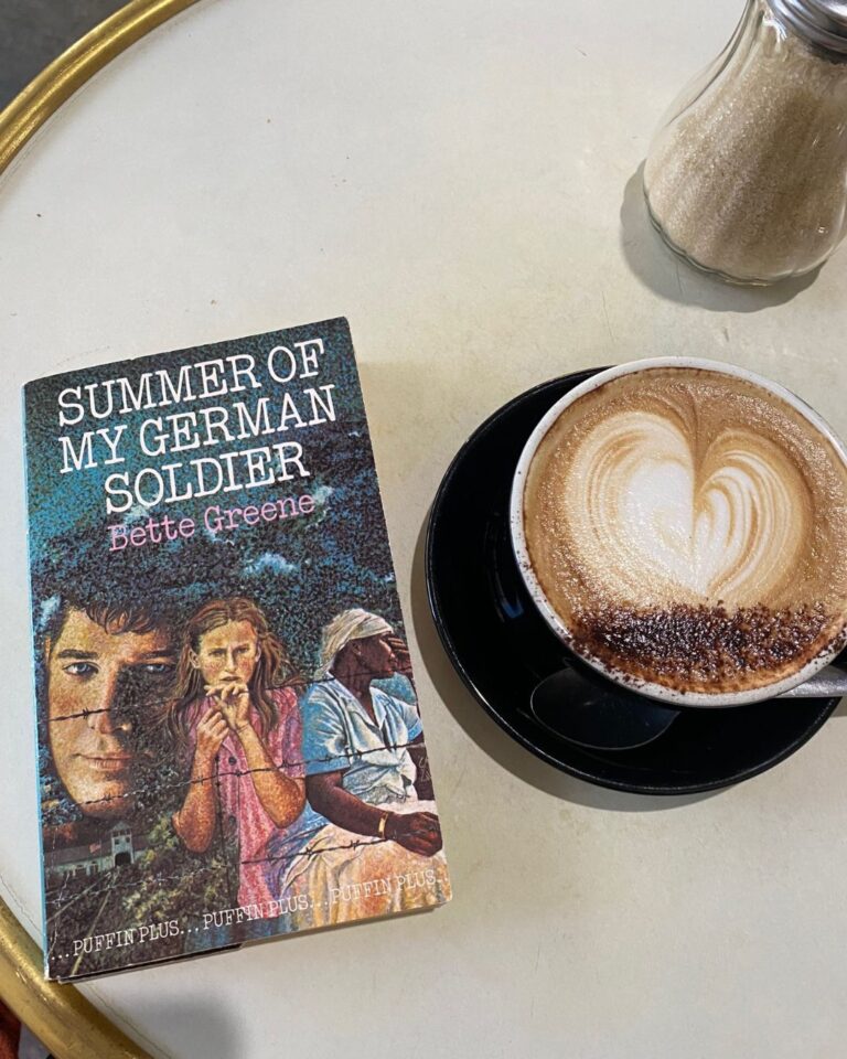 Summer of My German Soldier by Bette Greene book cover on a coffee table next to a cup of coffee
