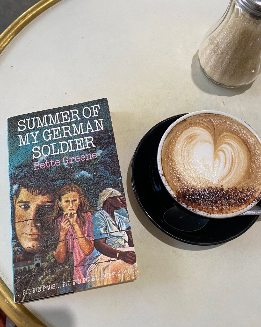 Summer of My German Soldier by Bette Greene book cover on a coffee table next to a cup of coffee