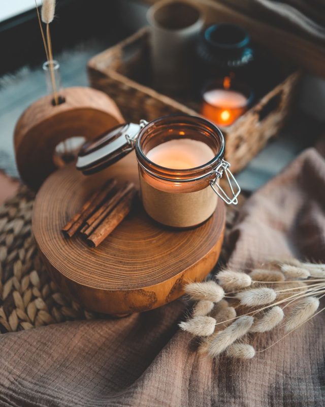 Meditation Space with linen, candle, soft light, dried flowers, and cinnamon on a wooden table.